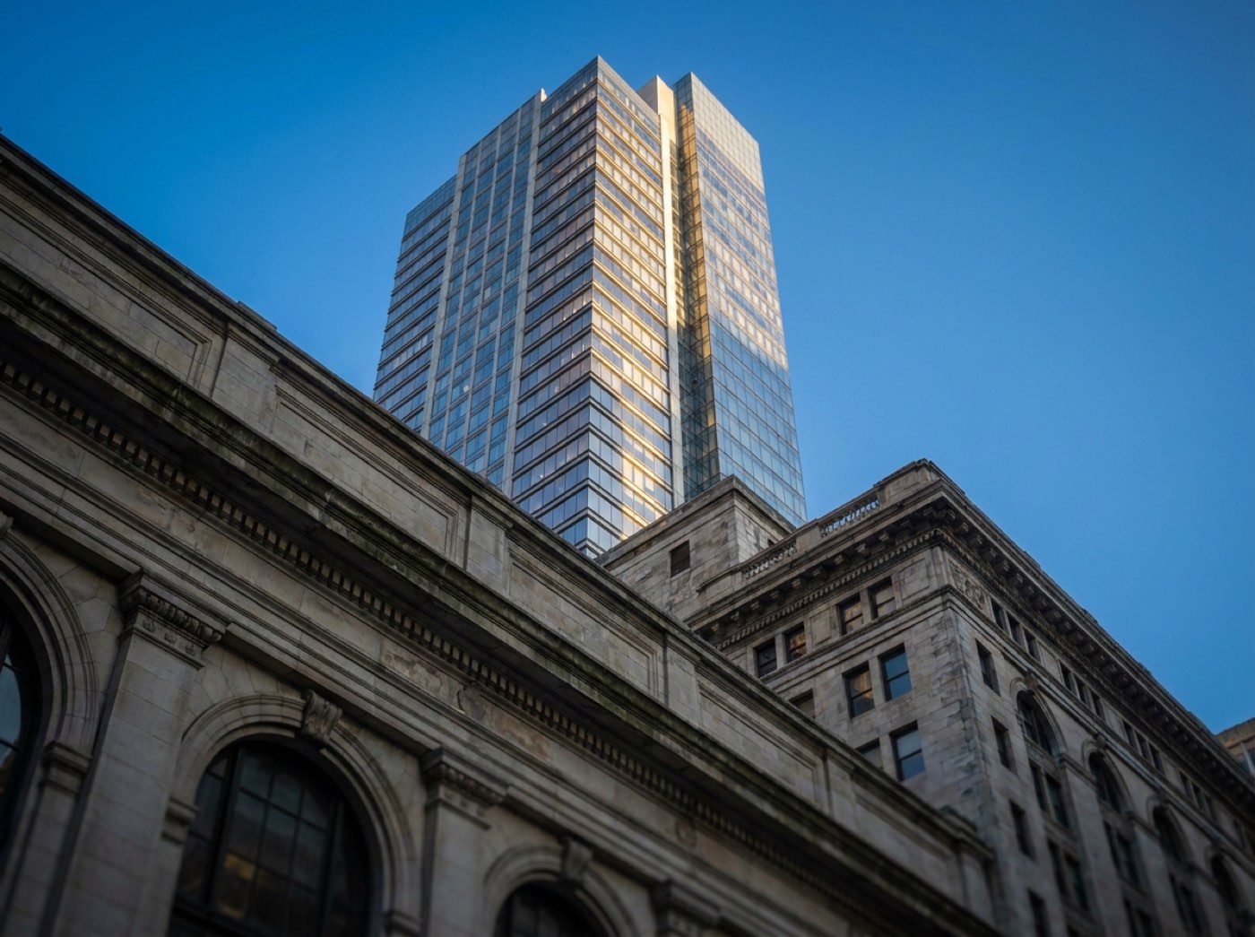 A Midtown Manhattan glass tower rising behind a limestone pre-war building