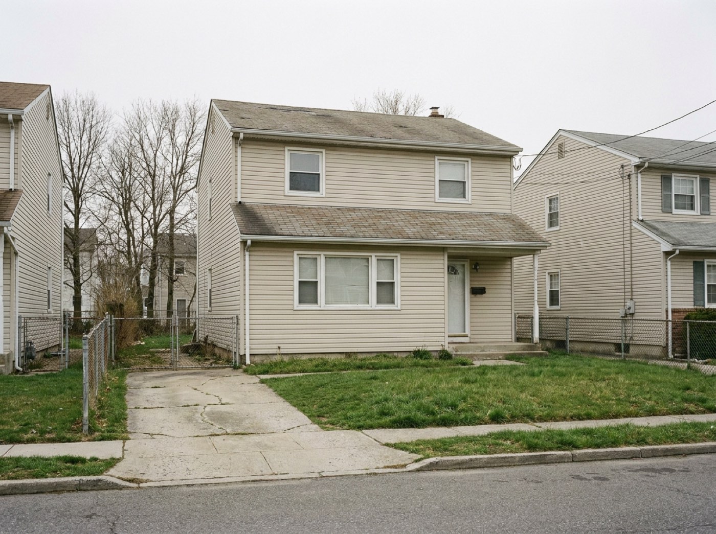 A detached two-storey Staten Island house with a driveway and a fenced side yard